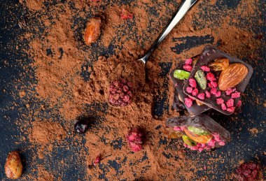 Kurutulmuş çilekli ev yapımı çikolata: ahududu, çilek ve fındık. Koyu arkaplan