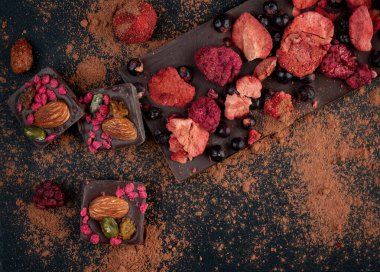 Kurutulmuş çilekli ev yapımı çikolata: ahududu, çilek ve fındık. Koyu arkaplan