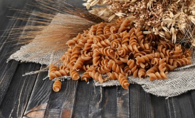 Tam tahıllı makarna sarmalı ya da fusilli, koyu kırsal arka plan. 