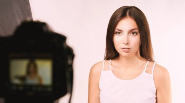 Fotoğraf makinesinin yanında oturan genç bir kadın. Video günlüğü yazarı