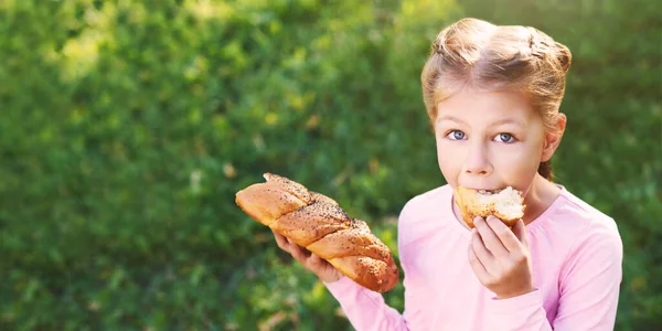 Dziewczynka je chleb. Portret kobiety na zewnątrz. Patrz w kamerę. — Zdjęcie stockowe