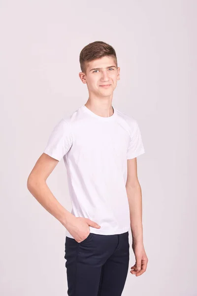 Retrato de adolescente. Hombre joven en el estudio. Mira la cámara. Camiseta blanca —  Fotos de Stock