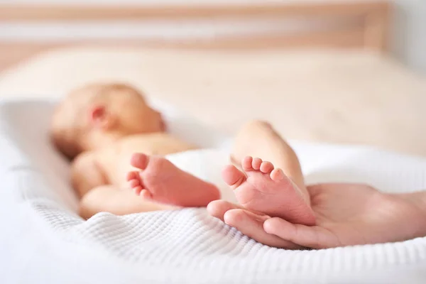 Newborn legs. Sister holding little feet. Two people