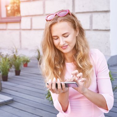 Telefonla mesajlaşan güzel bir genç kadın. Dışarıda mutlu bir kadın var.