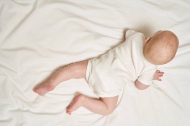 Yatakta yatan sevimli küçük çocuk. Çocukluk konsepti. Hafif arkaplan. Ciddi çocuk