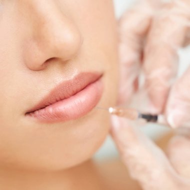 Spa salonunda dudak iğnesi. Doktor elleri. Yakından bak. Güzel bayan hasta.