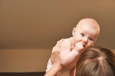Anne ellerinde sevimli küçük bir çocuk. Çocukluk konsepti. Gülümseyen çocuk