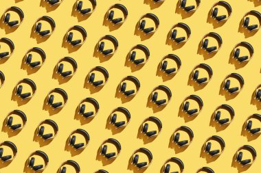 Parlak arkaplanda bir sürü aynı kulaklık var. Modern müzik konsepti