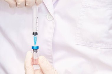 Eldivenlerde enjeksiyon olan şişeyi tutan doktor. Eczane laboratuvarı