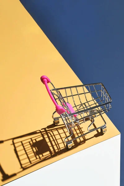 Carrello negozio su sfondo giallo e blu brillante. Moderno concetto di centro commerciale — Foto Stock