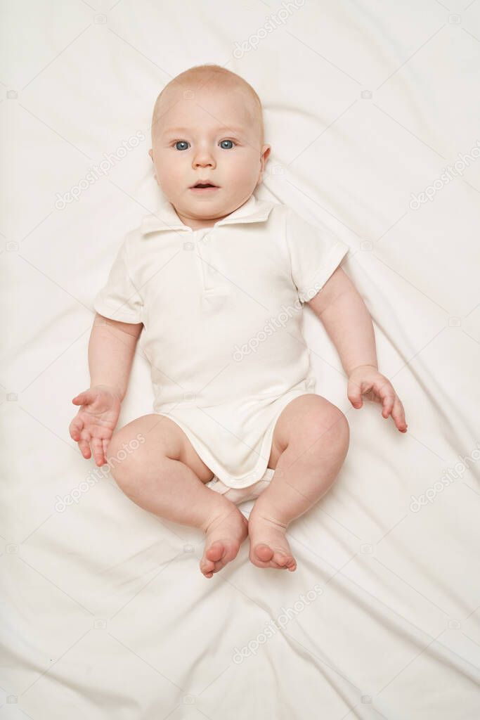 Cute small boy lying at bed. Childhood concept. Light background