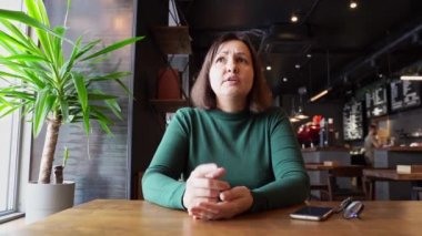 Güzel kadın kafede oturuyor ve konuşuyor..