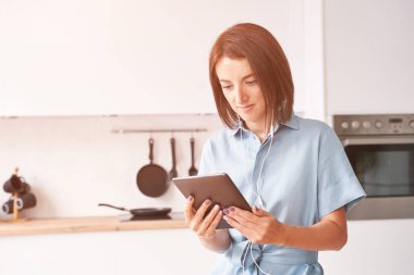 Genç bir kadın mutfakta oturuyor. Tablet üzerinde çalışıyorum. Çevrimiçi çalışma kavramı