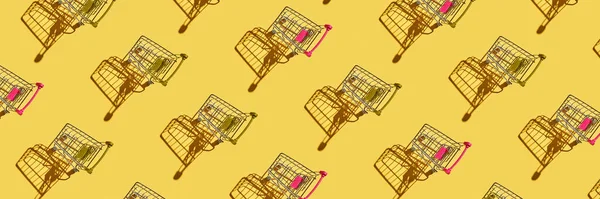 Many same shop trolley on yellow bright background. Modern mall concept