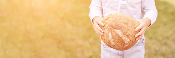 Ребенок держит круглый хлеб. Здоровое питание. Несу большую свежую булочку — стоковое фото