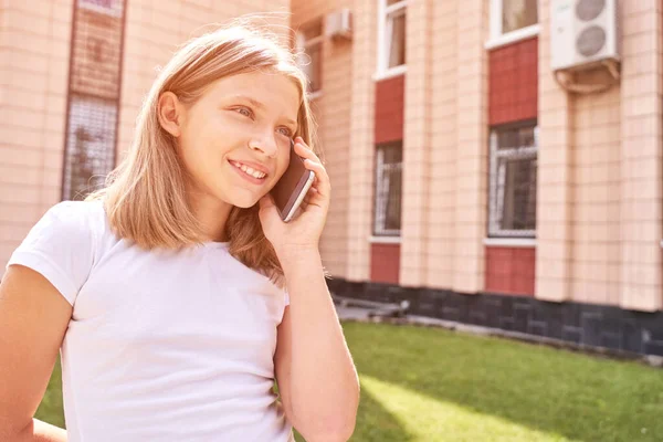 Bella ragazzina che parla. Tieni il telefono vicino alla faccia. I giovani sorridono — Foto Stock