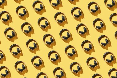 Parlak arkaplanda bir sürü aynı kulaklık var. Modern müzik konsepti