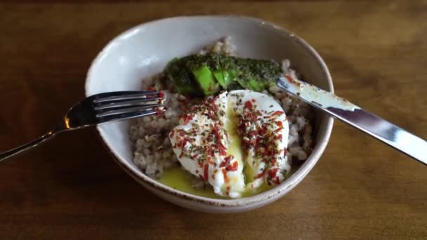 Comida saludable en la cafetería vegana. Alforfón verde con huevo escalfado y aguacate. — Vídeos de Stock