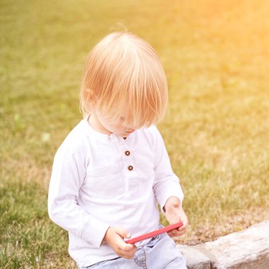 Küçük çocuk akıllı telefonuyla oynuyor. Dış meçhul portre