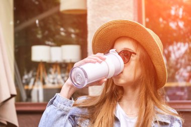 Güzel kız açık havada içecek içer. Kahveyi kendi fincanınla al. Gerçek insanlar.
