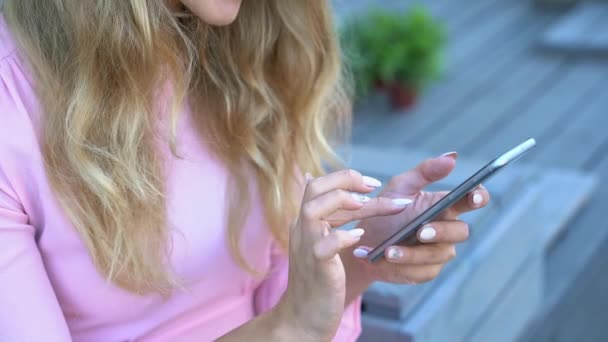 Hübsche junge Frau, die per Telefon SMS schreibt. Glückliche weibliche Person im Café draußen — Stockvideo