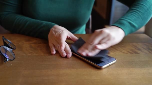 Las manos de mujer limpian el teléfono. Dispositivo limpio con pañuelos de papel negro. Vestido verde — Vídeos de Stock