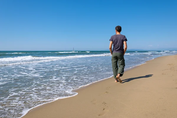 Mies kävelee rannalla — kuvapankkivalokuva