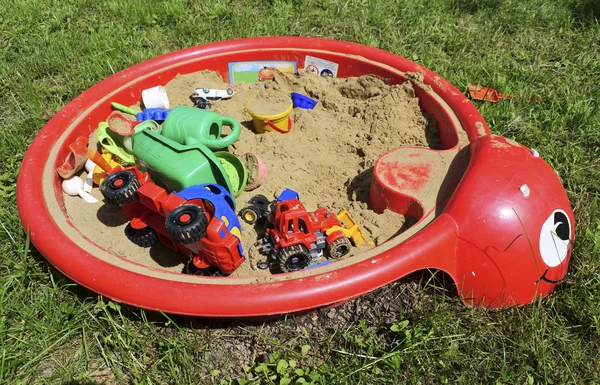 Sandbox per bambini con giocattoli sull'erba . — Foto Stock