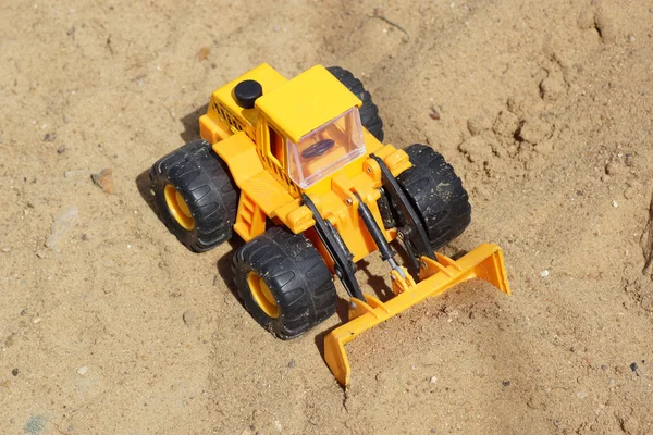 Toy yellow tractor on the sand. — Stock Photo, Image