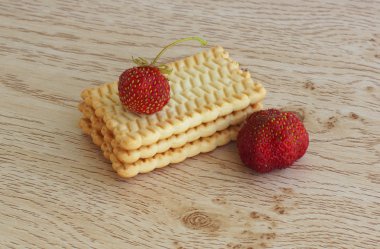 Tahta bir masanın üzerinde yatan çilek ile bisküvi. 