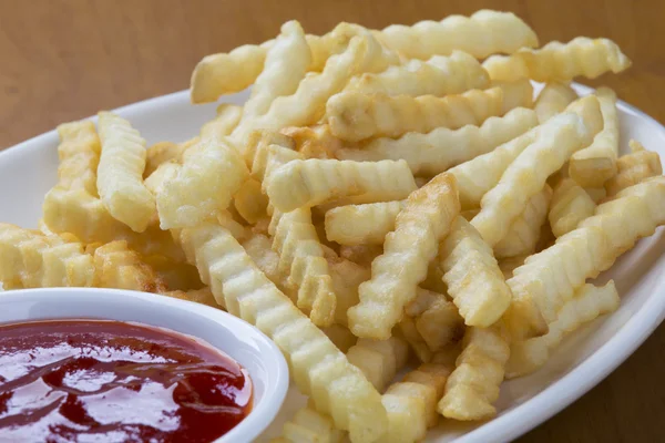 Delicious crinkle cut style french fries with ketchup — Stock Photo, Image