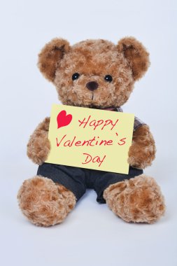 Beyaz bir arka plan üzerinde izole Happy Valentine's Day diyor sarı bir işaret tutan bir şirin ayıcık