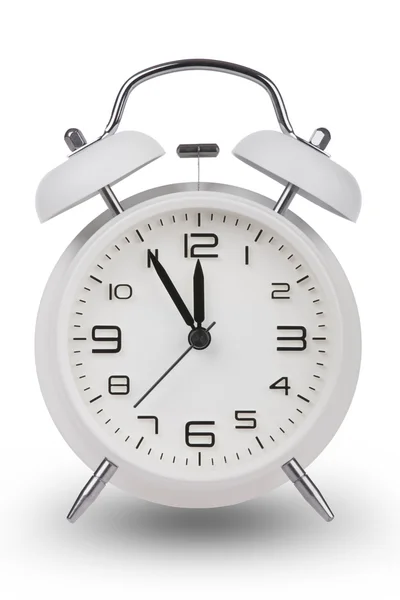 Reloj despertador blanco con las manos a 5 minutos hasta las 12. Ilustrando el tiempo se está acabando aislado sobre un fondo blanco — Foto de Stock