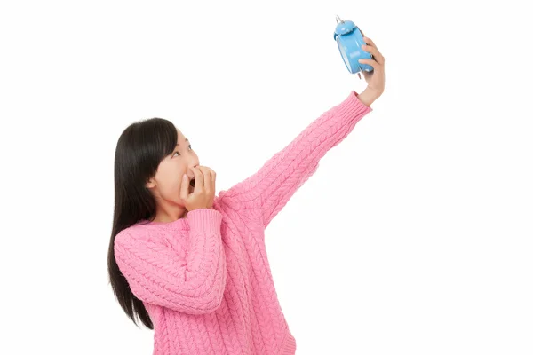 Beautiful Asian woman holding a blue alarm clock and looking surpresed or worried isolated on a white background — Stock Photo, Image