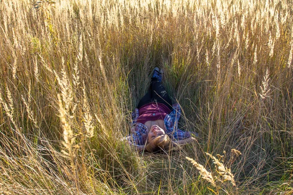 Una chica yace en una hierba sobre una espalda en un pueblo y mira al cielo Imagen de stock