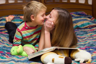 çocuk ve annesi bir yatakta yatarken bir kitap okumak