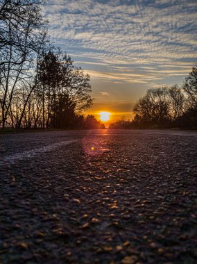 Asfalt yolun altında turuncu gün batımı, dikey fotoğraf