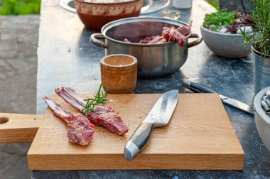 Biberiyeli, baharatlı lezzetli kuzu pirzolası ve tahta kesme tahtasında büyük bir bıçak. 