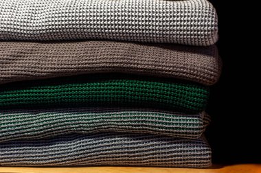 Ahşap rafta, siyah izole edilmiş örülmüş battaniye yığını.