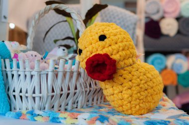 Büyük sarı örgü oyuncağı, komik kırmızı kabarık dudakları ve bulanık oyun odası arka planında diğer oyuncaklarla dolu bir sepeti var. 