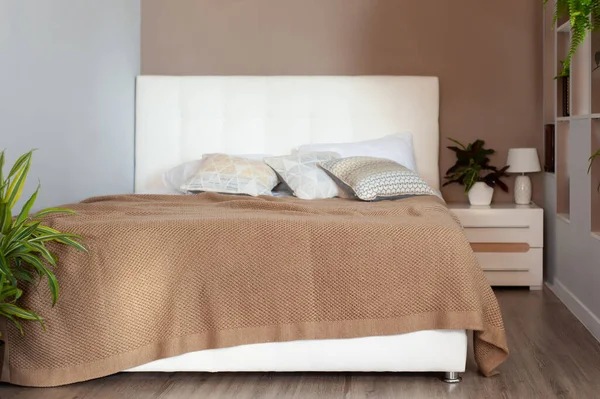 Gorgeous beige knitted blanket on bed in cozy bedroom