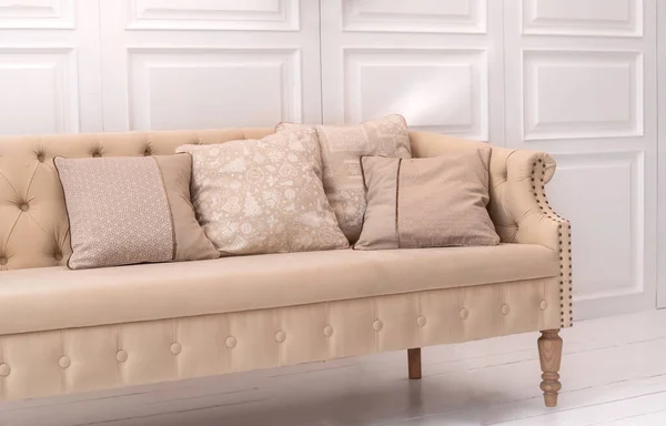 Interior design elements: beige cushions with Christmas pattern on beige old style couch in white room