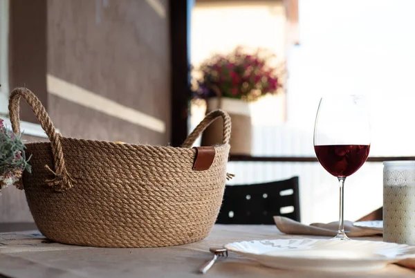 Jute basket and glass of red wine on a table on terrace