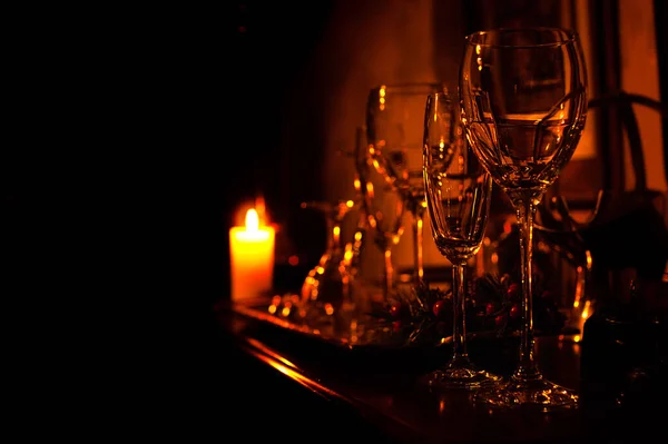 Crystal glasses on a shelf in candle light, black isolated