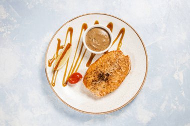 Beyaz tabak ve mavi arka plan manzaralı domates soslu balık bifteği.