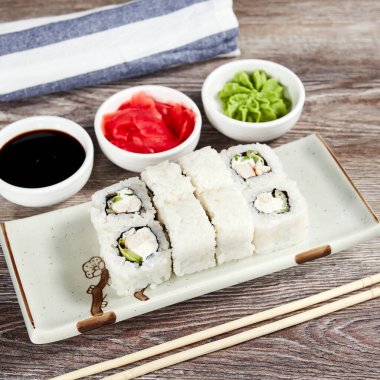 Japon suşisi, açık ahşap bir masada dikdörtgen bir tabakta yuvarlanır.
