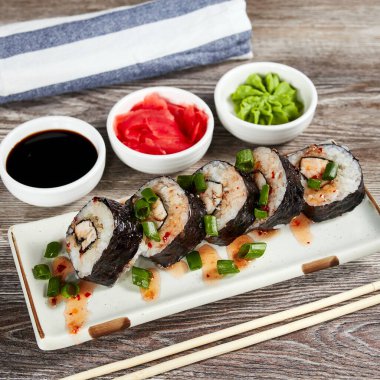 Japon suşisi, açık ahşap bir masada dikdörtgen bir tabakta yuvarlanır.