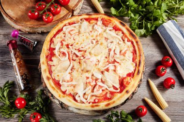 Sebze ve domatesli pizza, açık ahşap bir masada.