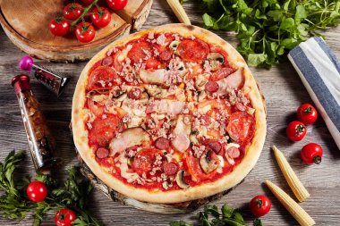 Sebze ve domatesli pizza, açık ahşap bir masada.