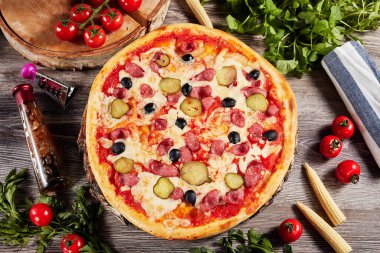 Sebze ve domatesli pizza, açık ahşap bir masada.